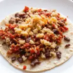 Authentic street-style Taco Campechano with steak, chorizo, and chicharron on a corn tortilla.