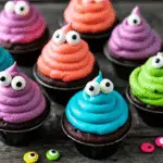 Halloween Monster Cupcakes with colorful frosting and candy eyes on a spooky table