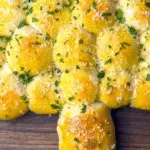Cheesy Pull-Apart Bread Christmas Tree with melted mozzarella and parsley on a wooden board