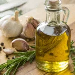 Easy garlic infused olive oil in a clear bottle with fresh garlic cloves and rosemary
