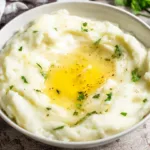 Creamy ultimate garlic mashed potatoes garnished with herbs in a bowl