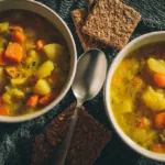 Bowl of comforting classic split pea soup with fresh herbs and vegetables.