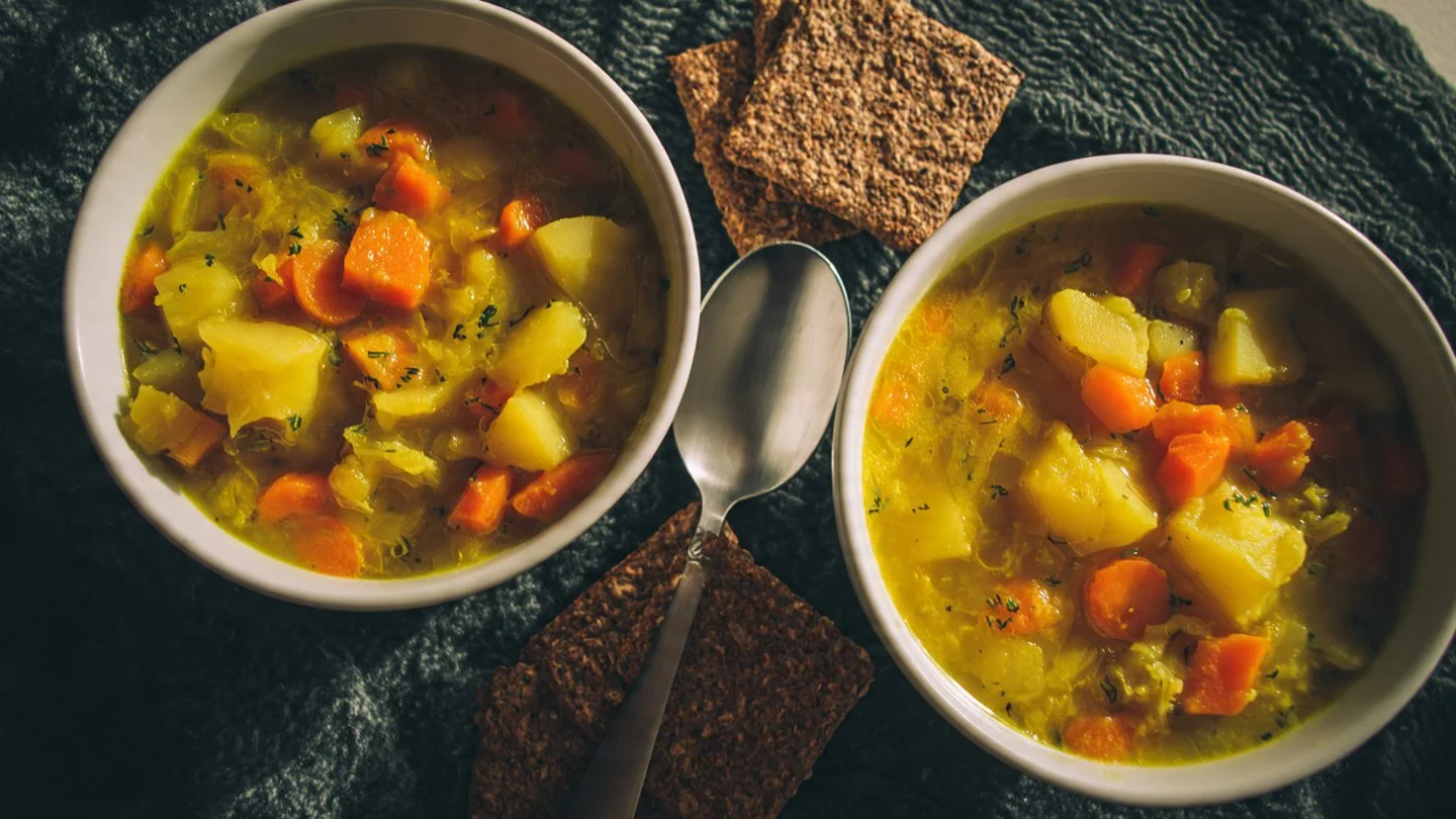 Bowl of comforting classic split pea soup with fresh herbs and vegetables.
