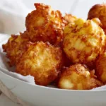 Delicious homemade corn fritters served on a plate with dipping sauce.