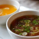 Delicious Japanese clear onion soup served in a bowl with garnishes.